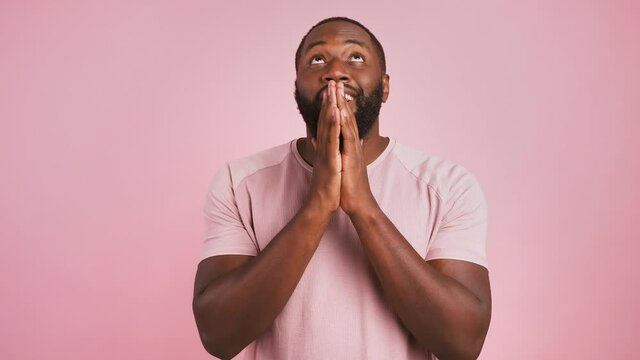 Black guy praying for success, making wish, hopes for fortune and good luck, and enjoying achievement