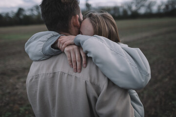 a couple in love walks in an open soybean field in the evening in cloudy weather