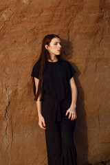 Young beautiful girl in black clothes walking on the beach. She walks along shore. A walk at sunset. Nobody around. Laugh, smile and enjoy summer Vacations