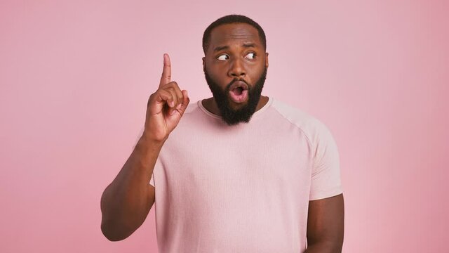 Creative thinking and inspiration. Emotional black guy having idea, pointing finger up, pink background