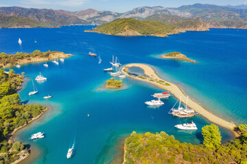 aerial view to long sand cape with beautiful lagoon with sailing boats and mountains on horizon in Turkey 