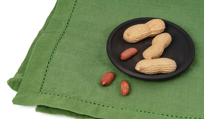 peanuts in a clay plate on a green napkin, white background