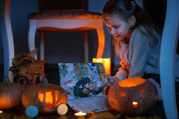 A little girl reads a fairy tale in the evening by the light.  The girl is illuminated by candles...
