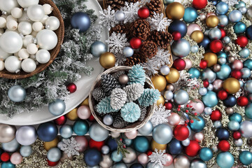 Top view christmas decorations centerpiece with garland and balls near a basket with pine cones, isolated on a heap of colorful and shiny balld
