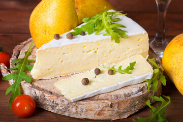 Brie cheese with cherry tomatoes, pear and arugula on a wooden table