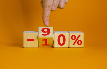 Hand turns a cube and changes the expression '-10 percent' to '-90 percent'. Beautiful orange background, copy space. Business concept.