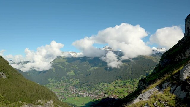 White cumulus clouds rolling above mountains and green valley