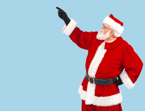 Santa Claus isolated on blue is pointing at something.