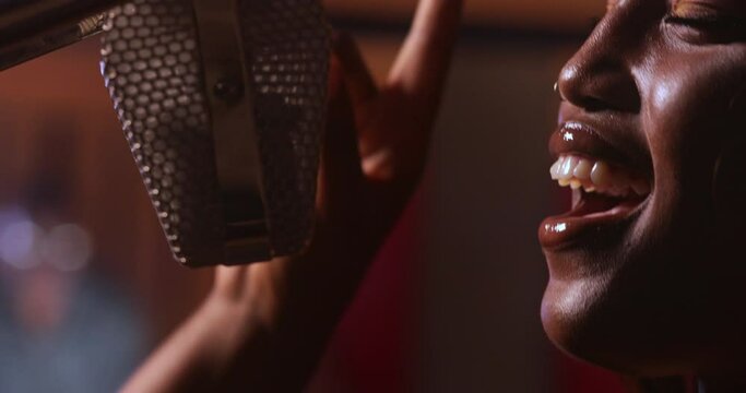 African-american female artist singing on microphone in music studio