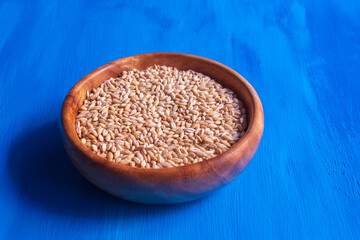 In a wooden deep bowl lies a fresh pearl cereal for cooking porridge