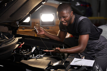afro american guy repairing car hood and make notes in notebook, alone, wearing uniform