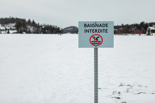 Signboard of baignade interdite written in french meaning no swimming with illustrator on ice layer with no people around