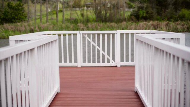 static shot of the balcony with white fense and pink ground by the pond.