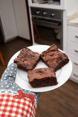 Brownies on a plate. Fresh pastries out of the oven held by chef with oven gloves / oven mitts / baking gloves. Perfect for bakeries or online dessert shops.