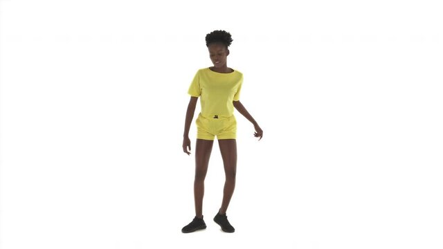 Young African woman dancing on white background. B-girl fast moving legs, doing quick steps, shaking upper body, dancing shuffle. Hip-hop movements.