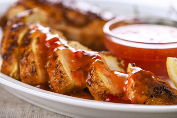 Baked chicken breast, cut into slices, with a spicy sweet and sour sauce. Close-up