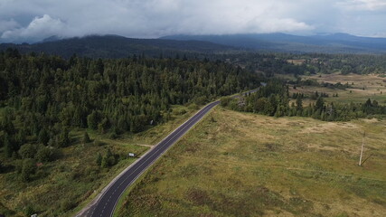 Aerial view descending over a mountain road covered by fog at sunrise