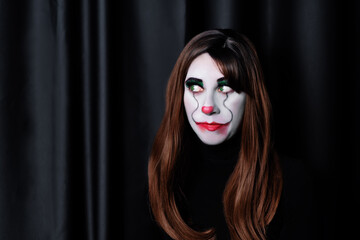 Brown haired woman clown with green eyes on a black background for Halloween
