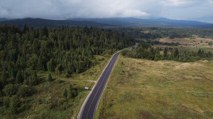 Aerial view descending over a mountain road covered by fog at sunrise