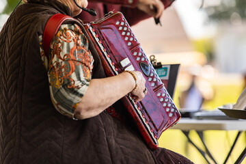 Selective focus of mature person wearing and playing accordion musical instrument with reference of...