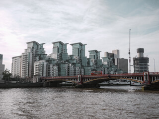 Fototapeta na wymiar Red bridge over the thames with apartment blocks