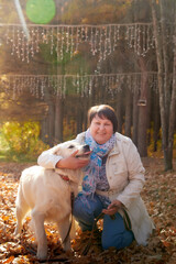 A plump woman with a white Labrador dog walking in a Park or forest on a Sunny autumn day.
