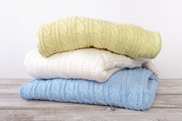 Stack of cozy comfortable homely clean washed knitted sweaters in pastel colors, laundry and washing clothes concept