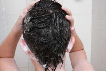 Naklejka premium Hygienic procedures and healthy habits of a preteen boy - taking shower and washing hair with shampoo