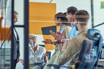 Great result. Group of multi ethnic business people clapping hands and celebrating success while standing together in modern office