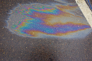 Obraz premium Colorful gas stain on wet asphalt. Oil stain caused by a leak under a car or truck.