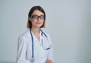 Professional woman doctor in a medical gown and glasses with a stethoscope around her neck