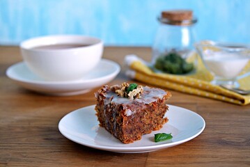 Dessert, a portion of carrot cake with walnuts and almonds on a white plate. Decorated with walnuts and icing.
