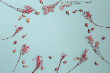 Creative layout with pastel pink flowers on turquoise desktop background, top view, place for text.