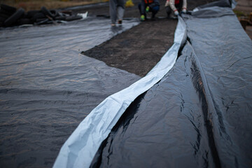 Roof waterproofing. Building construction. A waterproof film is applied to the roof of the house....