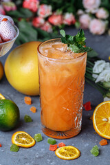 Summer fresh cold drink beverages. Ice Lemonade in the jug and lemons and orange with mint on the table outdoor. Orange lemonade in a glass