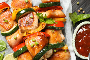 Delicious chicken shish kebabs with vegetables and ketchup on black table, closeup