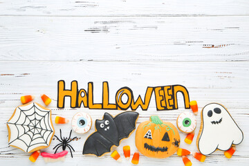 Text Halloween with gingerbread cookies and candies on white wooden table