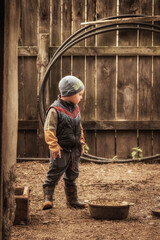 Brutal child boy farmer standing in barn in rustic poultry house in countryside farm as farming...