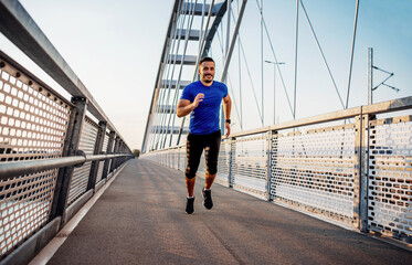 Jogging. Young man running over the bridge. Sport, fitness, recreation concept