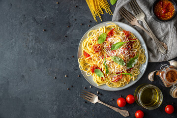 Italian dinner with pasta on ceramic plate with ingredients around on black background. Flat view. Top view.