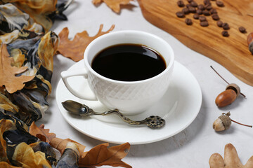Acorn coffee with fall oak leaves on gray background. Coffee substitute without caffeine. Closeup. Horizontal format.