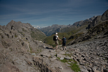 Fototapeta na wymiar a man and a woman descend from the Col de Chaviere towards the Peclet Polset hut facing Mont Blanc