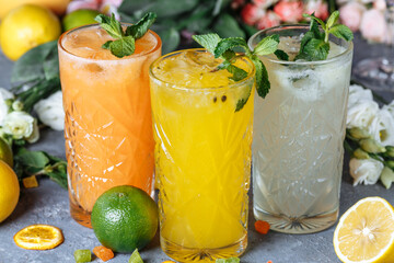 Summer fresh cold drink beverages. Ice Lemonade in the jug and lemons and orange with mint on the table outdoor. Orange lemonade in a glass