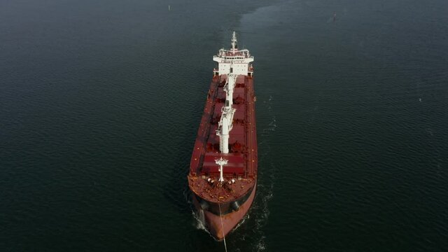 Drone shot at a large cargo ship with two towing ships escorted to the port of Gdansk, Poland. 
Aerial view of a large cargo ship in the baltic sea, the ship sails to port, accompanied by two tug boat