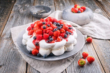 Modern Style traditionelle australische Pavlova Torte mit Baiser Creme und Früchten angeboten als close-up auf einem Design Teller