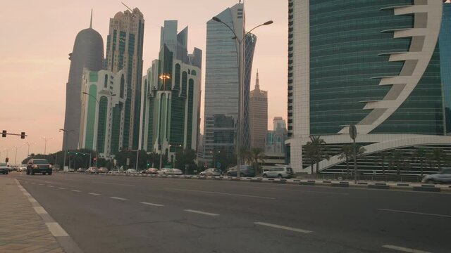 Doha corniche in Qatar at Sheraton park intersection sunset shot showing West bay skyscrapers  ,cars in the street  and clouds in sky in background  