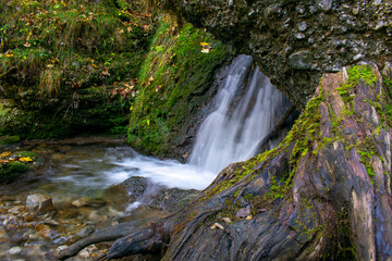Obraz premium Bachlauf unter Hinanger Wasserfall kurz vor der Felswand mit Baumstumpf rechts