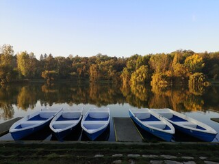 Fototapeta na wymiar Autumn morning in the park. Blue boats on the lake
