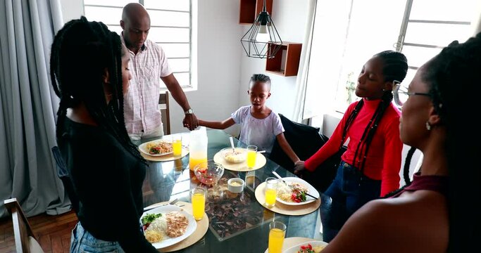 Religious African family gathered together in prayer before eating
