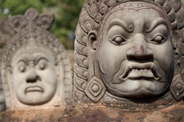 Close up of Asuras (demons) statues in a row at the Bayon Temple entrance gate